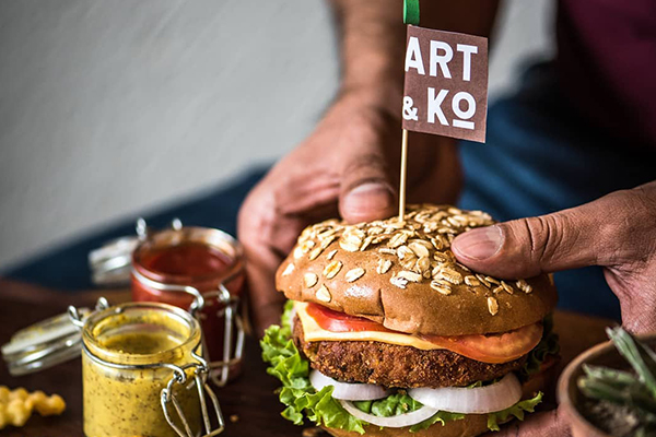 Man holding Burger at Art & Ko - Read N Dine Cafe